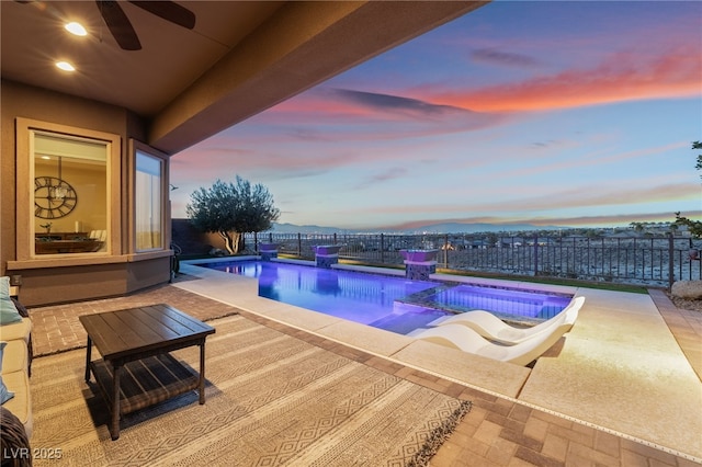 pool at dusk featuring a patio area and ceiling fan