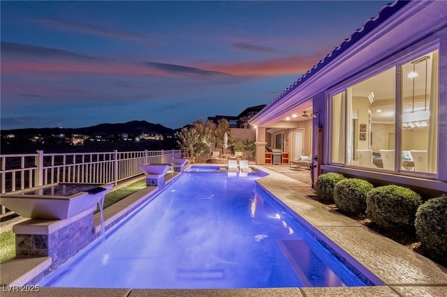 pool at dusk featuring a patio and pool water feature