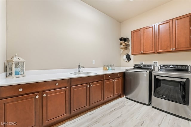 laundry area with sink, light wood-type flooring, cabinets, and independent washer and dryer