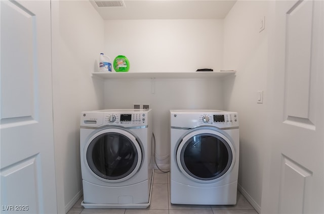 clothes washing area with light tile patterned floors and washer and dryer