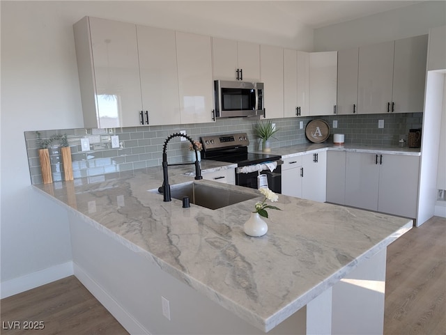 kitchen with white cabinetry, appliances with stainless steel finishes, sink, and kitchen peninsula