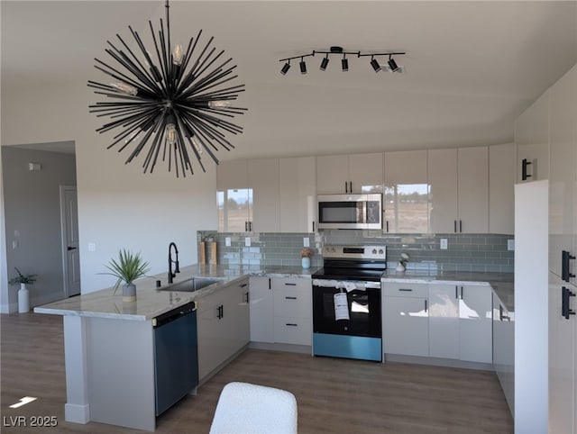 kitchen featuring sink, white cabinetry, appliances with stainless steel finishes, kitchen peninsula, and hardwood / wood-style floors