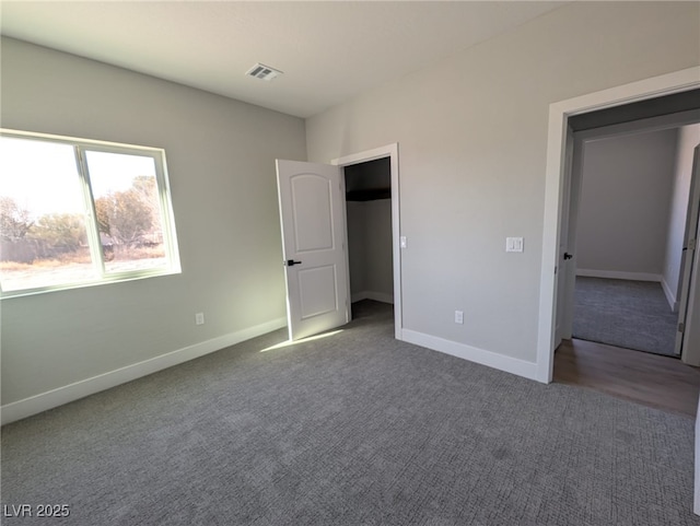 unfurnished bedroom with a walk in closet and carpet floors