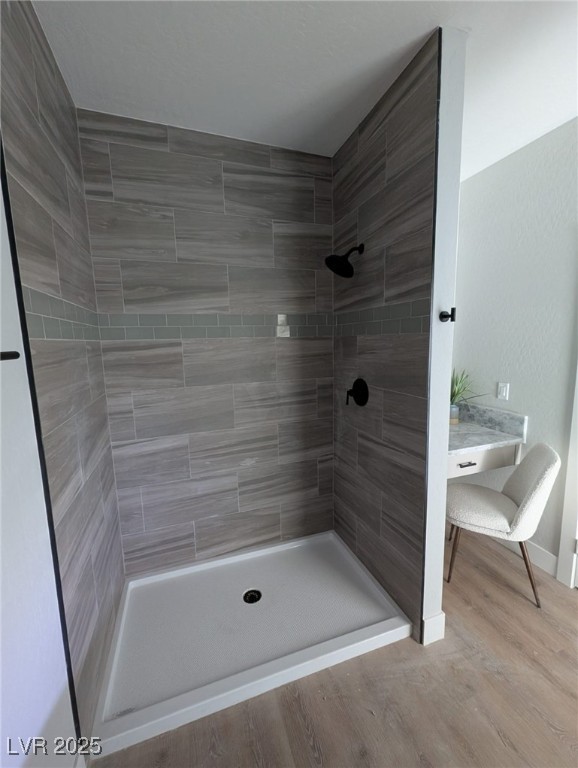 bathroom featuring a tile shower and wood-type flooring