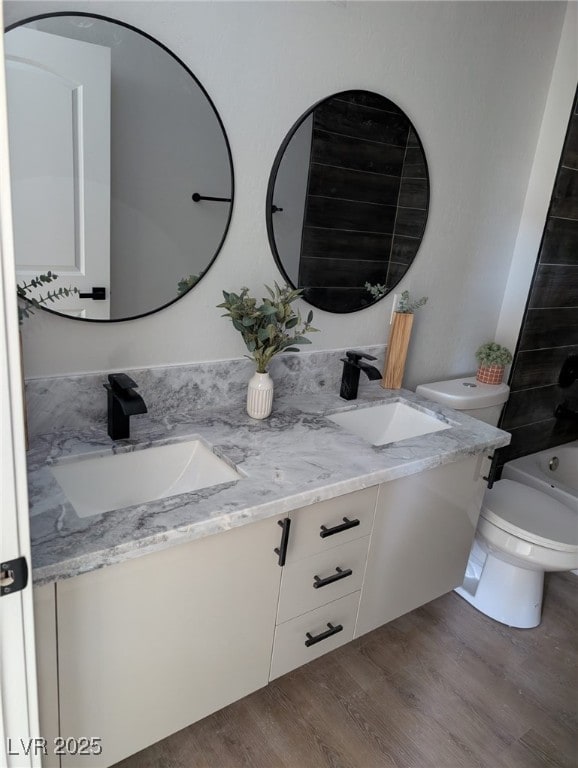 full bathroom featuring hardwood / wood-style flooring, vanity, toilet, and bathtub / shower combination