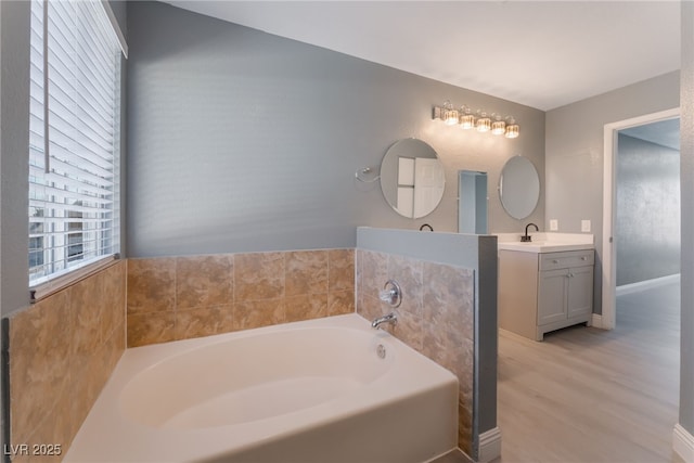 bathroom with vanity, a bath, and wood-type flooring