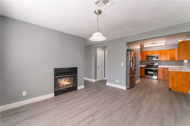 unfurnished living room with sink, light wood-type flooring, and a multi sided fireplace