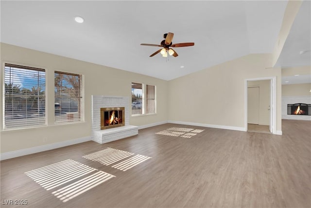 unfurnished living room with ceiling fan, a brick fireplace, lofted ceiling, and light wood-type flooring