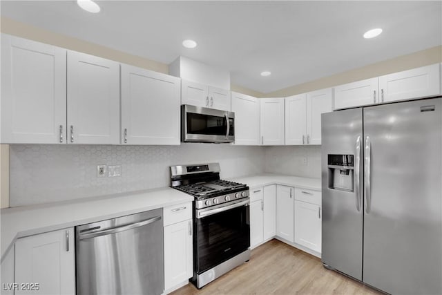 kitchen with white cabinetry, appliances with stainless steel finishes, light hardwood / wood-style floors, and decorative backsplash