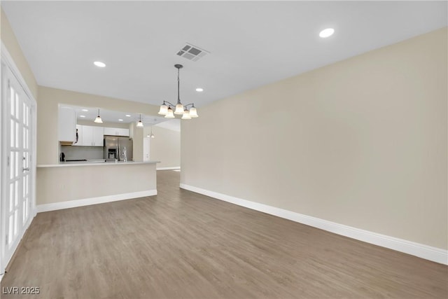 unfurnished living room featuring a chandelier and hardwood / wood-style floors