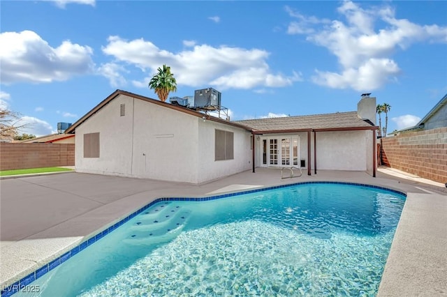 view of pool with cooling unit, a patio area, and french doors