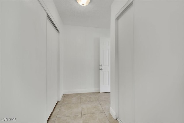 hall with light tile patterned flooring and a textured ceiling