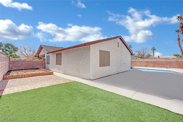 rear view of house featuring a fenced in pool, a patio, and a lawn