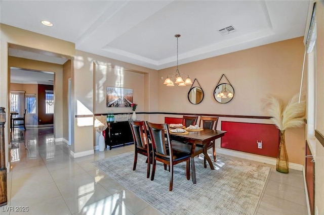 dining area featuring a raised ceiling, tile patterned flooring, and a notable chandelier