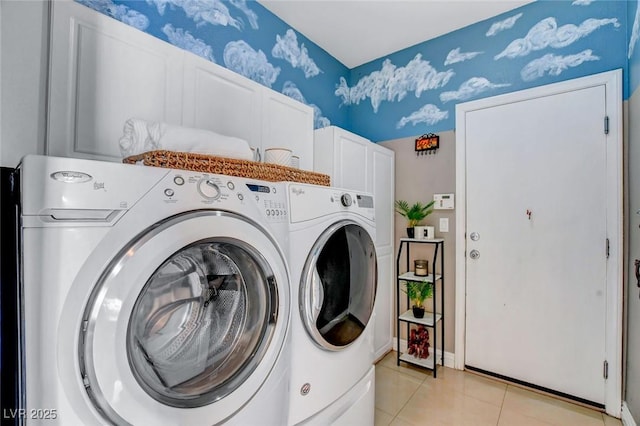 clothes washing area with light tile patterned floors, cabinets, and washing machine and clothes dryer