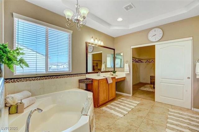 bathroom with tile patterned flooring, vanity, a raised ceiling, a bath, and an inviting chandelier