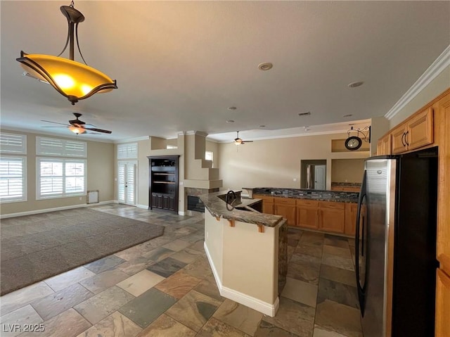 kitchen with kitchen peninsula, stainless steel fridge, decorative light fixtures, crown molding, and a breakfast bar