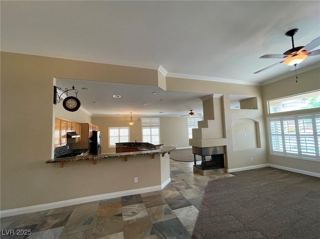 kitchen with a kitchen bar, kitchen peninsula, a multi sided fireplace, ornamental molding, and refrigerator