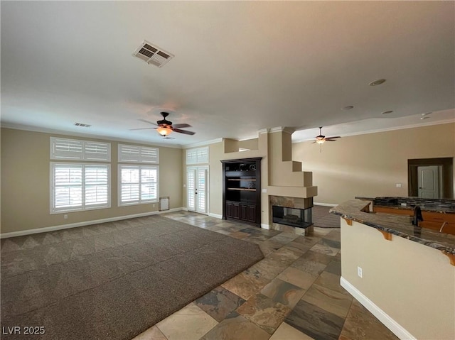 unfurnished living room with ceiling fan, ornamental molding, and a fireplace