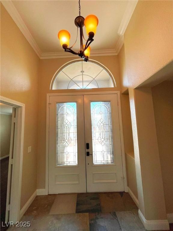 entryway with an inviting chandelier, ornamental molding, and french doors