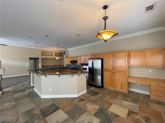 kitchen featuring stainless steel fridge, built in desk, dark stone counters, crown molding, and a breakfast bar