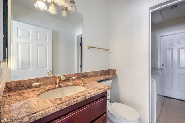 bathroom with toilet, vanity, a notable chandelier, and tile patterned flooring