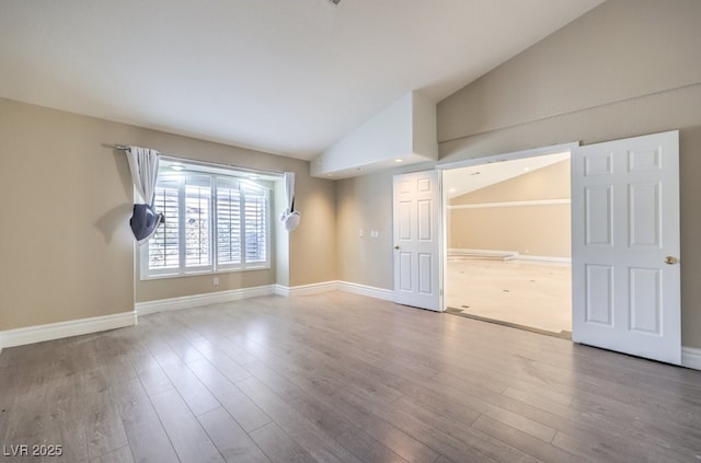 unfurnished room featuring hardwood / wood-style flooring and lofted ceiling