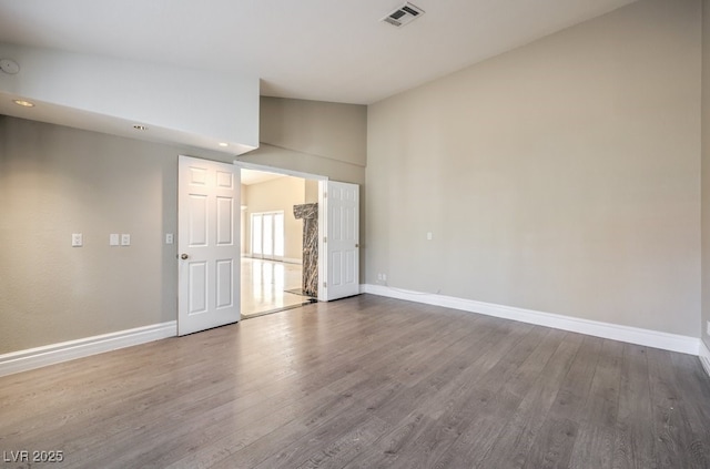 unfurnished room featuring hardwood / wood-style flooring and lofted ceiling