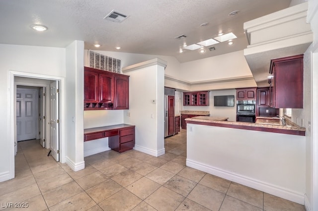 kitchen with kitchen peninsula, vaulted ceiling, sink, oven, and a textured ceiling