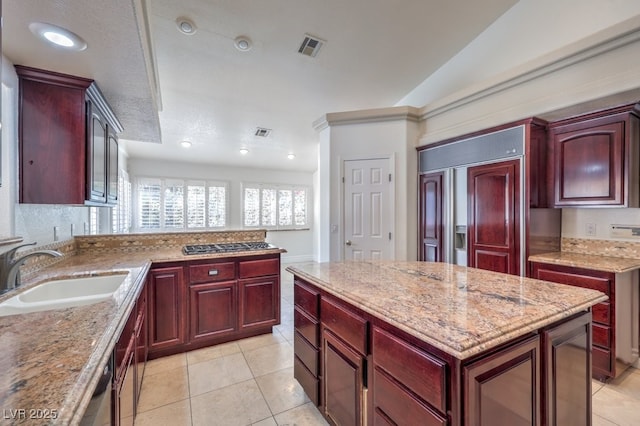 kitchen with a center island, light stone countertops, light tile patterned floors, sink, and vaulted ceiling