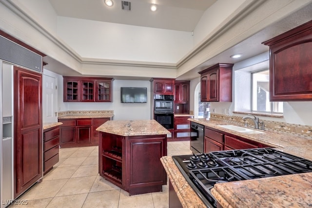 kitchen featuring a center island, black appliances, sink, light tile patterned flooring, and a tray ceiling