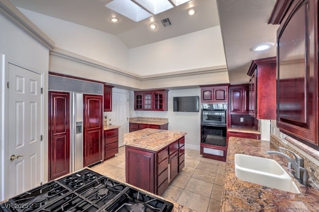 kitchen with light stone countertops, paneled refrigerator, a center island, stovetop, and sink