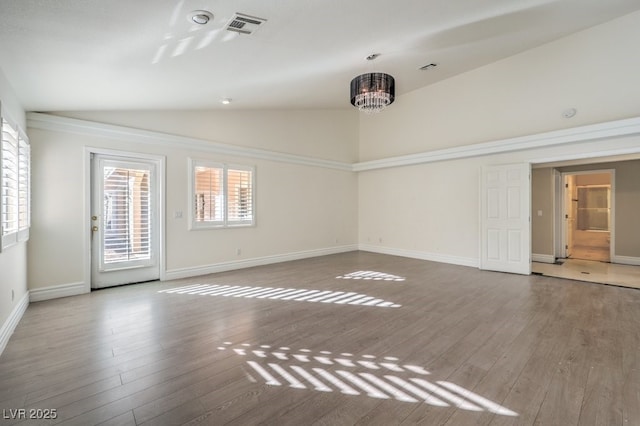 empty room featuring vaulted ceiling, a chandelier, and hardwood / wood-style floors