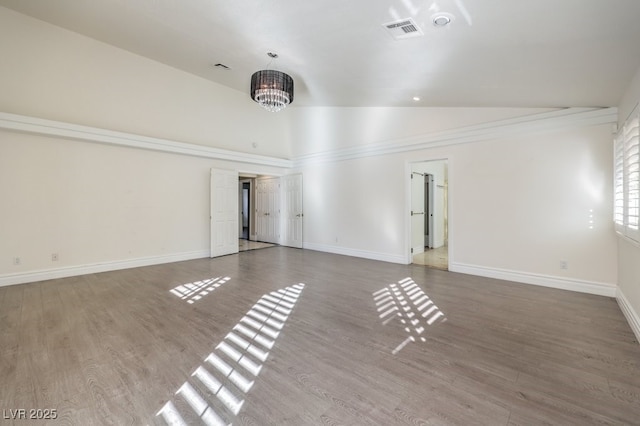 empty room featuring hardwood / wood-style flooring, a chandelier, and lofted ceiling