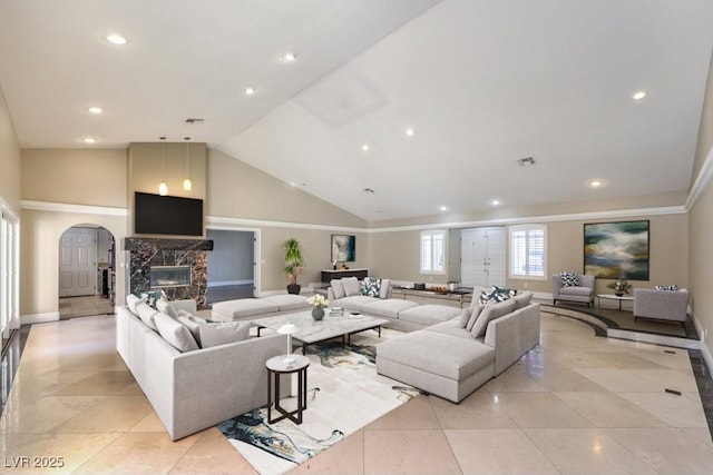 living room featuring high vaulted ceiling, light tile patterned floors, and a high end fireplace