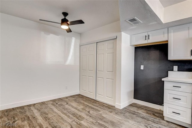 kitchen featuring ceiling fan, a textured ceiling, white cabinetry, and hardwood / wood-style floors