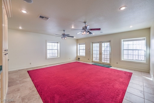 tiled spare room featuring a textured ceiling, ceiling fan, plenty of natural light, and french doors