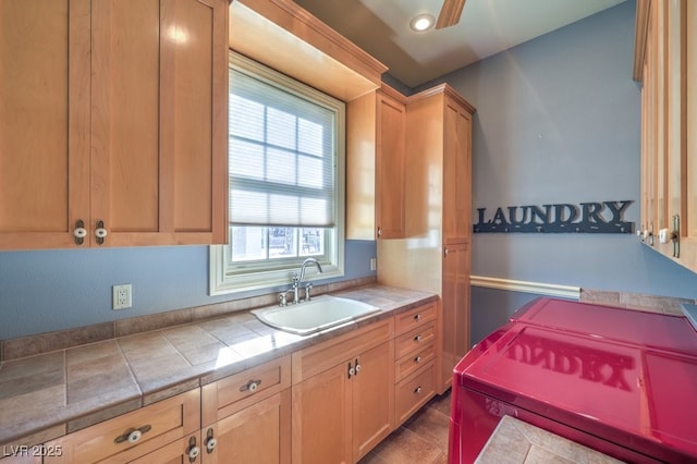 kitchen with tile counters, a wealth of natural light, ceiling fan, and sink