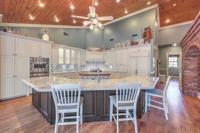 kitchen featuring tasteful backsplash, white cabinets, light stone countertops, and a large island