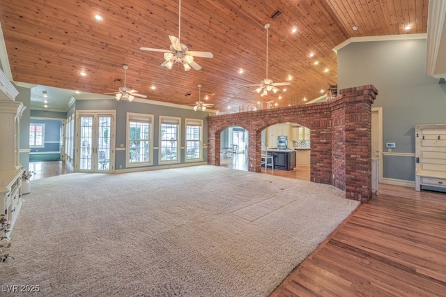 unfurnished living room featuring wooden ceiling, ornamental molding, french doors, and high vaulted ceiling