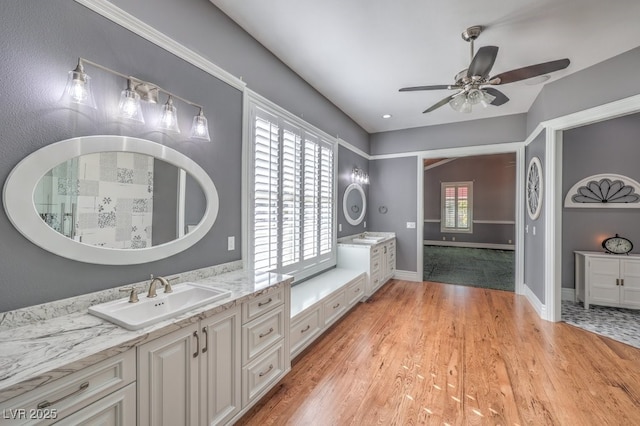 bathroom with ceiling fan, a wealth of natural light, wood-type flooring, and vanity