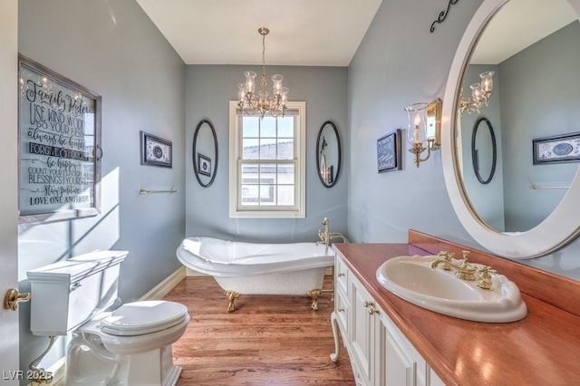 bathroom featuring vanity, a tub, toilet, a chandelier, and hardwood / wood-style flooring