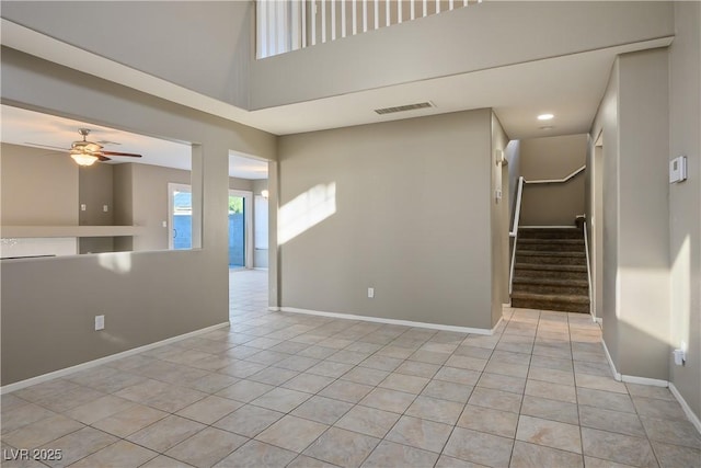 empty room with ceiling fan, light tile patterned floors, and a high ceiling