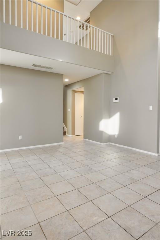 empty room featuring a high ceiling and light tile patterned floors