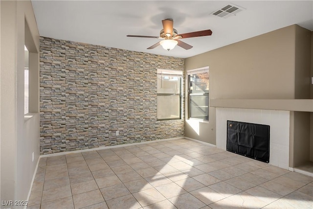 unfurnished living room featuring ceiling fan, light tile patterned floors, and a tile fireplace