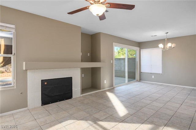 unfurnished living room with light tile patterned floors, a fireplace, and ceiling fan with notable chandelier