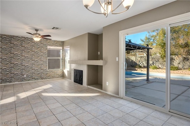 unfurnished living room with light tile patterned floors and ceiling fan with notable chandelier