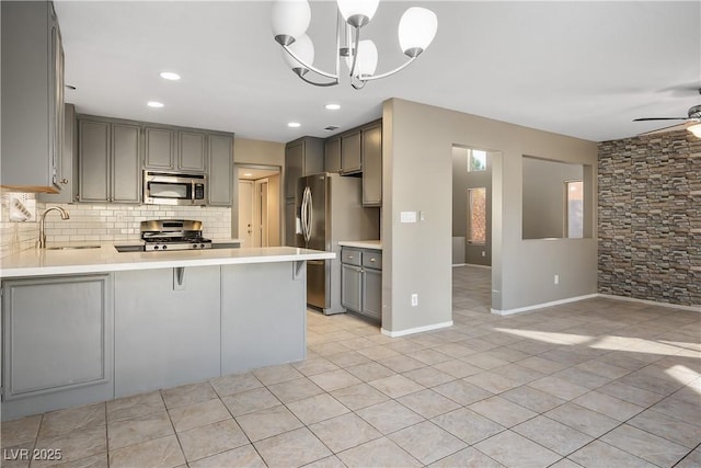 kitchen featuring appliances with stainless steel finishes, decorative light fixtures, decorative backsplash, sink, and kitchen peninsula