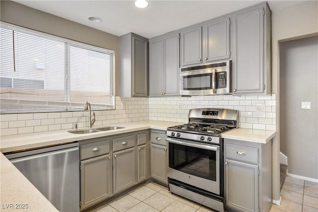 kitchen featuring light tile patterned flooring, gray cabinets, appliances with stainless steel finishes, and sink