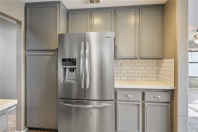 kitchen featuring stainless steel refrigerator with ice dispenser, decorative backsplash, and gray cabinets